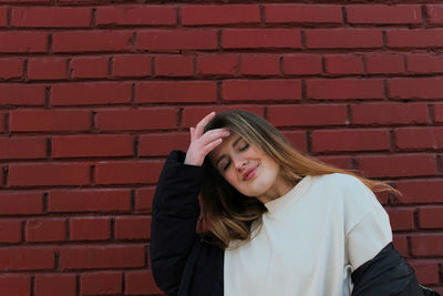 Smiling woman standing by brick wall