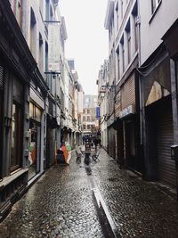 Wet street amidst buildings in city during rainy season