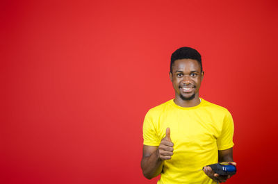 Portrait of smiling young man against red background