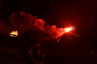 Person wearing costume while holding sparks at night
