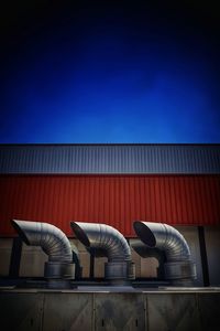 Low angle view of industry against clear blue sky