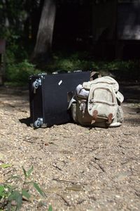 Suitcase and backpack on field during sunny day