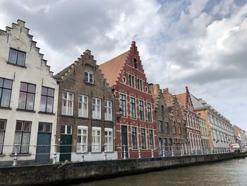 Low angle view of buildings by river against sky