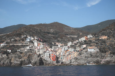 Aerial view of buildings in town by sea against sky