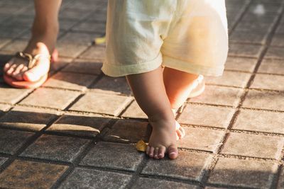 Low section of woman with child standing on footpath