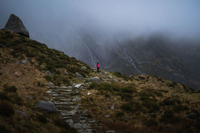 Woman standing on mountain during foggy weather