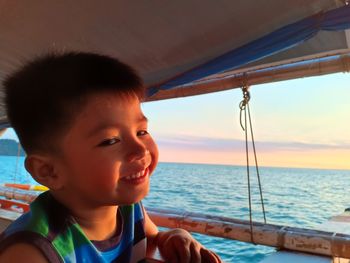 Portrait of smiling boy on boat in sea against sky