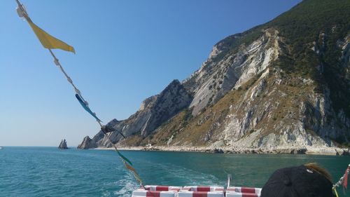 Scenic view of sea by mountain against sky