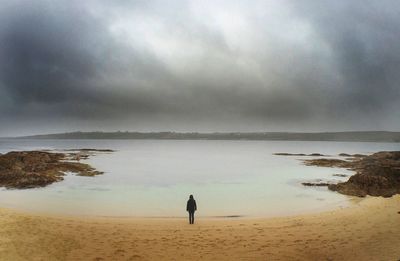 Scenic view of beach against cloudy sky