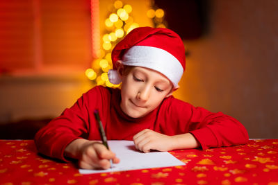 Girl looking away while sitting on table at home