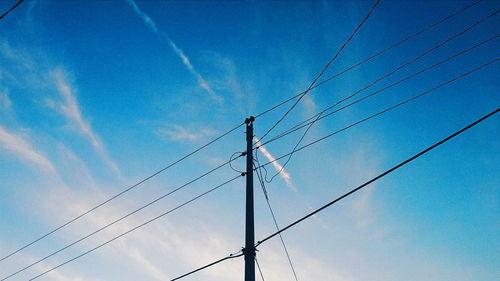 Low angle view of electricity pylon against blue sky