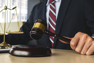 Midsection of judge holding gavel in courtroom