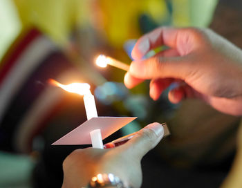 Close-up of hand holding lit candles