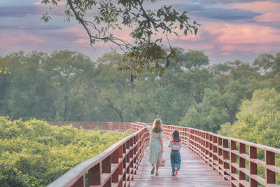 Rear view of man walking on footbridge