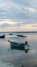 Boats in sea against cloudy sky