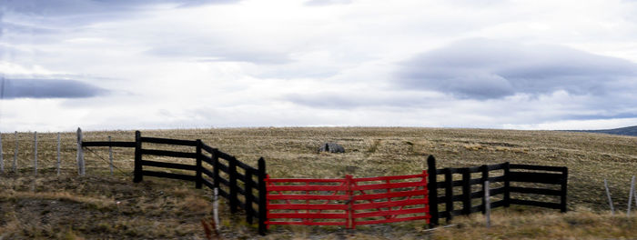 Wooden fence on field against sky