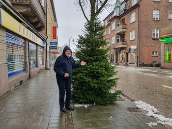 Man standing on footpath by street in city