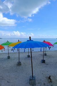 Colorful umbrellas at beach against sky