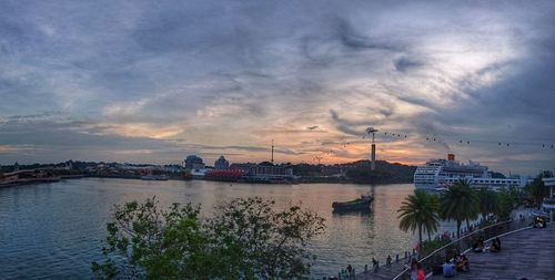 View of city at waterfront against cloudy sky