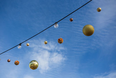 Low angle view of lighting equipment hanging against blue sky
