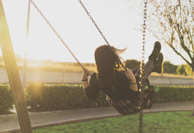 Rear view of woman playing on swing 