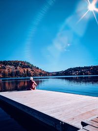 Woman sitting by swimming pool in lake against sky