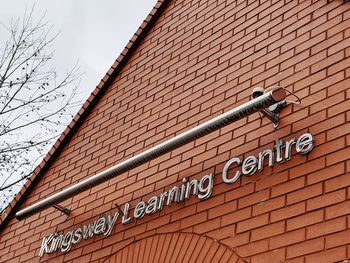 Low angle view of text on wall against building