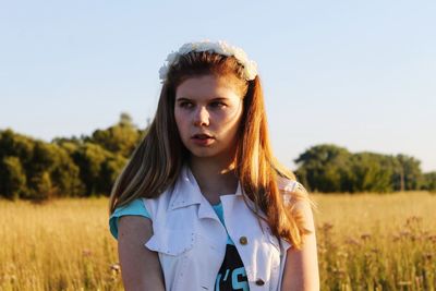 Portrait of beautiful woman standing on field against clear sky