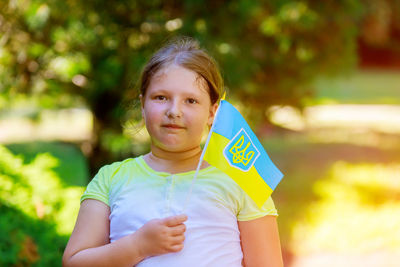 Portrait of girl holding flag while standing outdoors