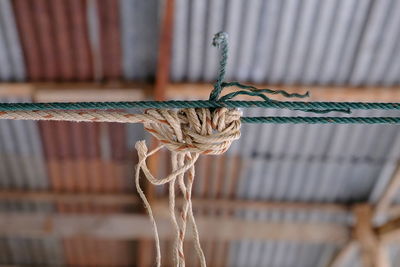 Close-up of rope tied on metal against wall