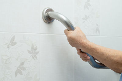 Close-up of man holding hands against white wall