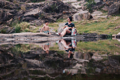 People sitting on rock by lake