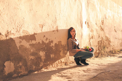 Full length of woman sitting on wall