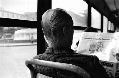 Rear view of man sitting by window