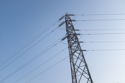 Low angle view of electricity pylon against clear blue sky