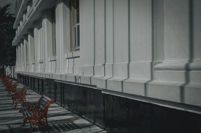 Empty bench on footpath against building