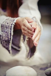 Close-up of woman rubbing hands over dough at kitchen counter