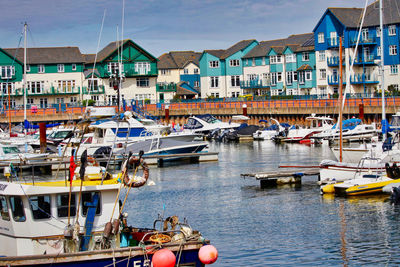 Boats moored at harbor by buildings in city