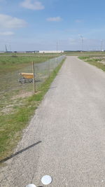 Road amidst field against sky