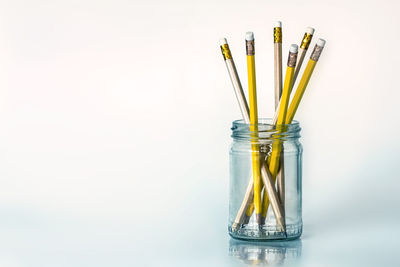 Close-up of pencils in jar on white background