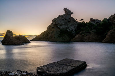 Rock formation by sea against clear sky