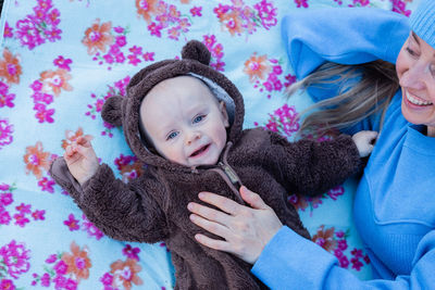 Portrait of smiling young woman looking to her  happy baby boy in teddy bear jumpsuit.