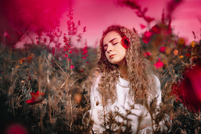Portrait of beautiful young woman against red plants in summer