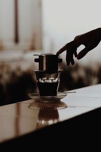 Cropped hand holding coffee on table