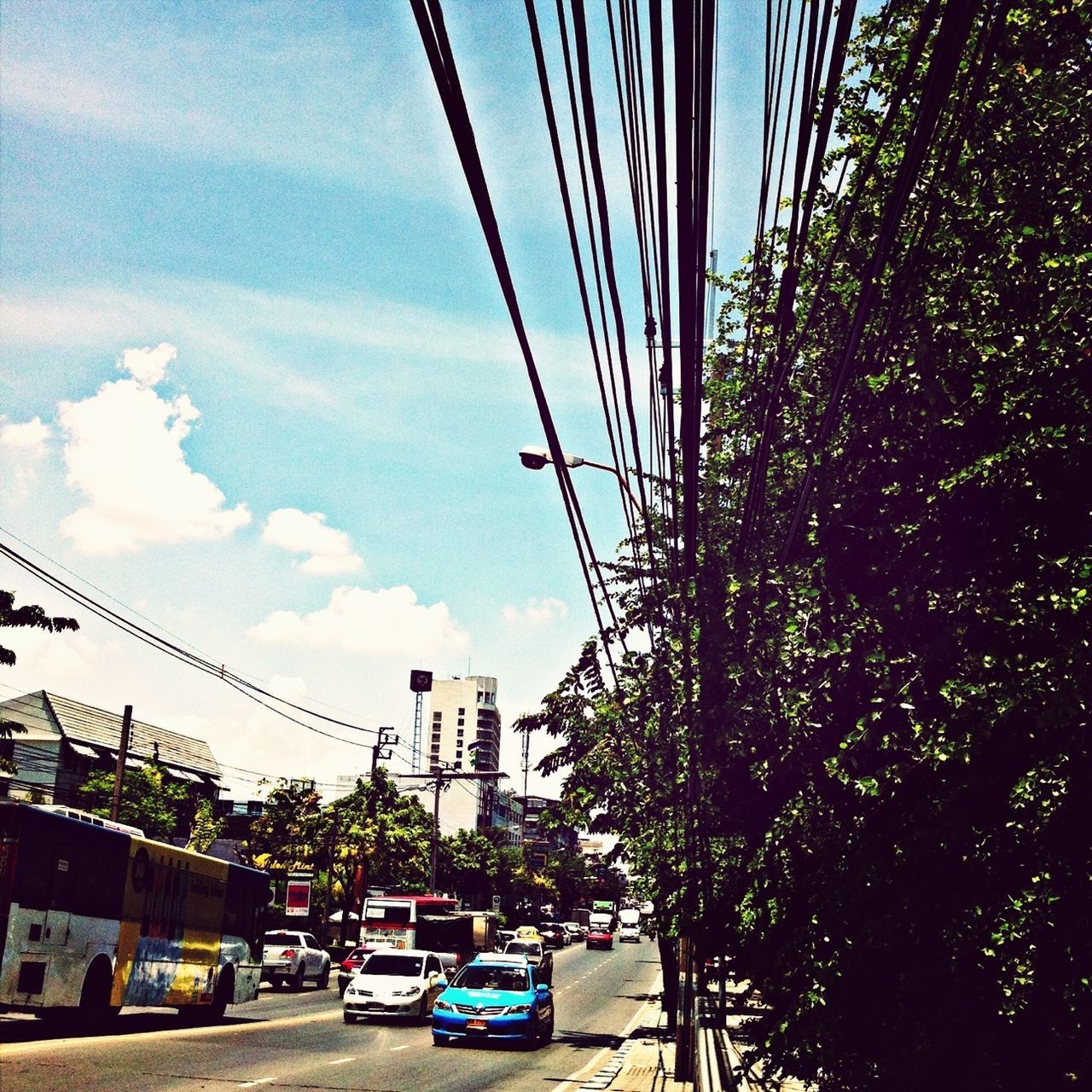 car, transportation, land vehicle, mode of transport, road, street, sky, tree, power line, building exterior, traffic, built structure, on the move, electricity pylon, architecture, city, cable, street light, low angle view, outdoors