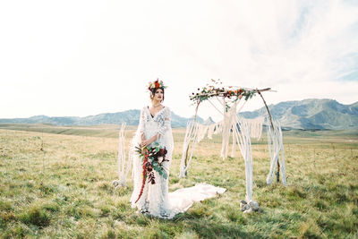 Rear view of woman standing on field against sky