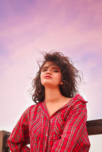 Portrait of beautiful young woman standing against sky