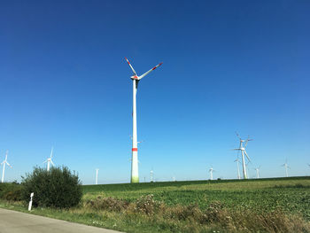 Windmill on field against clear blue sky