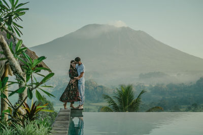 Rear view of women standing on mountain against sky