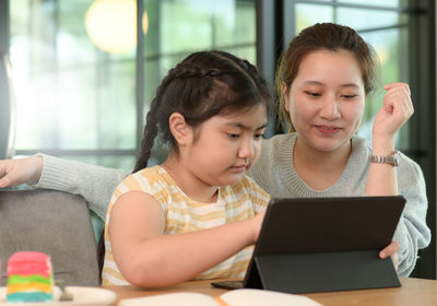 Friends using laptop while sitting on sofa at home